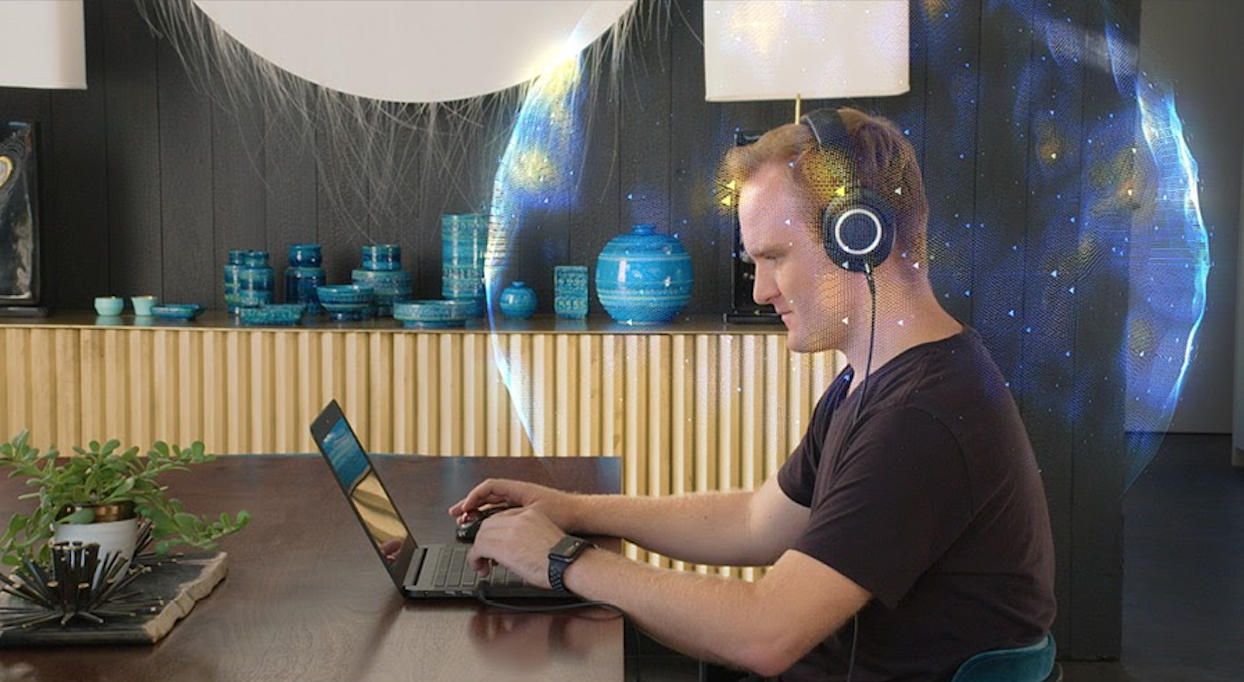 A man using headphones and a laptop with a bubble around his head