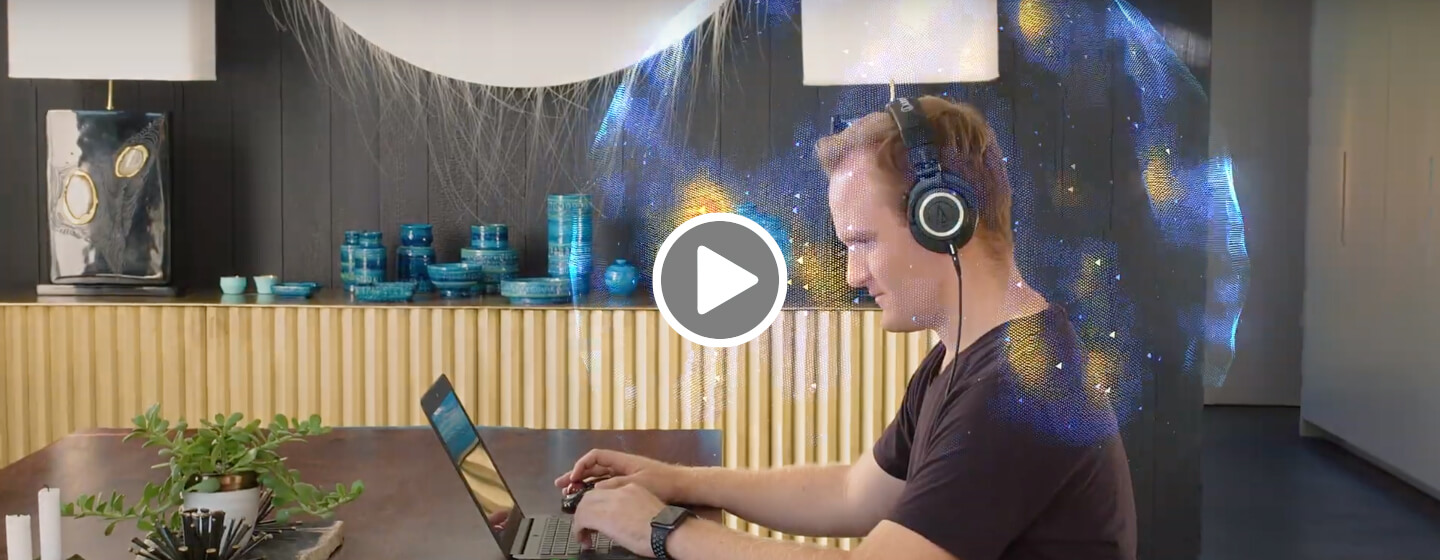 Man sitting at laptop using headphones and THX Spatial Audio