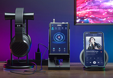 The FiiO BTR7 with headphones and a smartphone sitting on a desk